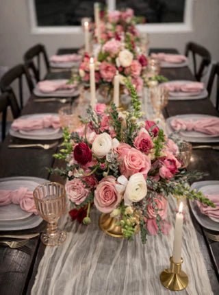 Elegant dining table set with floral centerpieces, candles, and silverware.