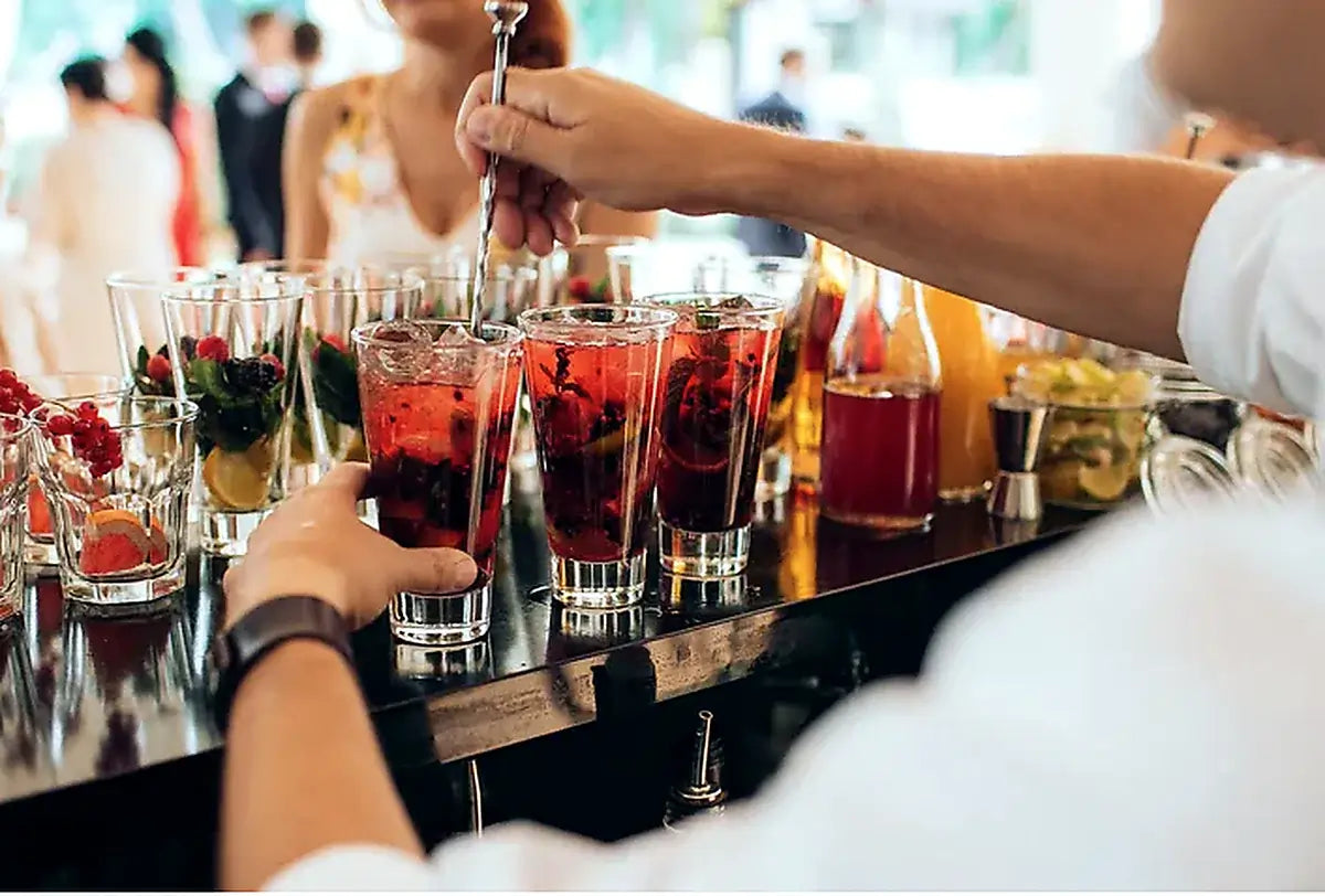 Bar setting with drinks being prepared, people in the background