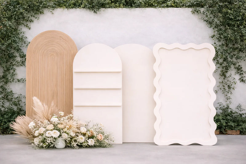 Three decorative photo frames against a white wall with greenery
